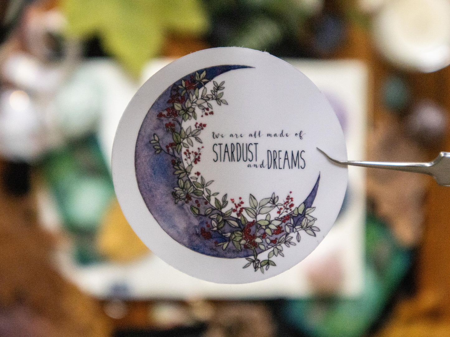 Close-up of Stardust Dreams sticker with crescent moon and wildflowers.